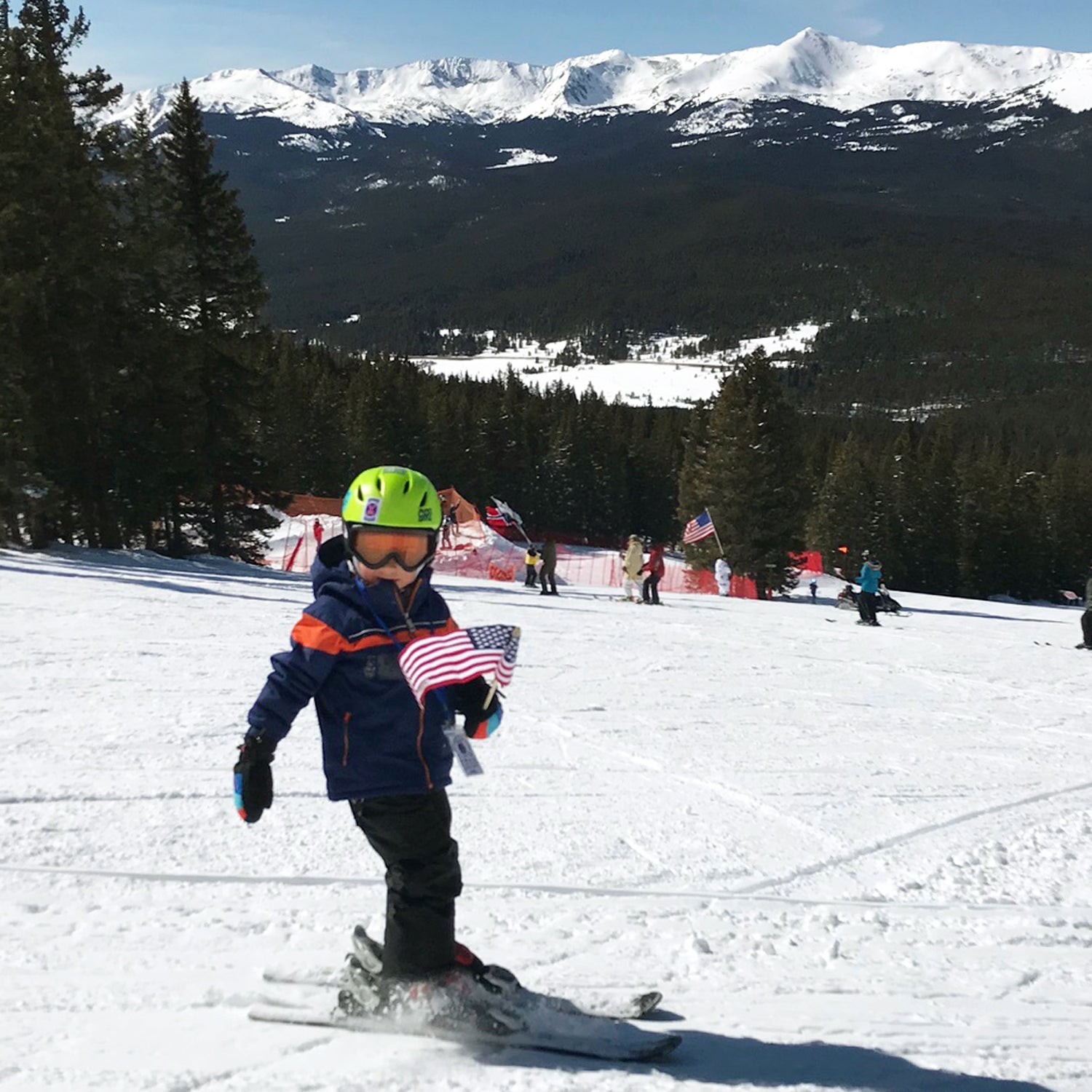 The author’s son Lachlan holding an American flag as he and others participate in an event called “skiing the serpentine”; everyone follows the person in front of them in a giant snake formation until they reach the bottom of the hill.