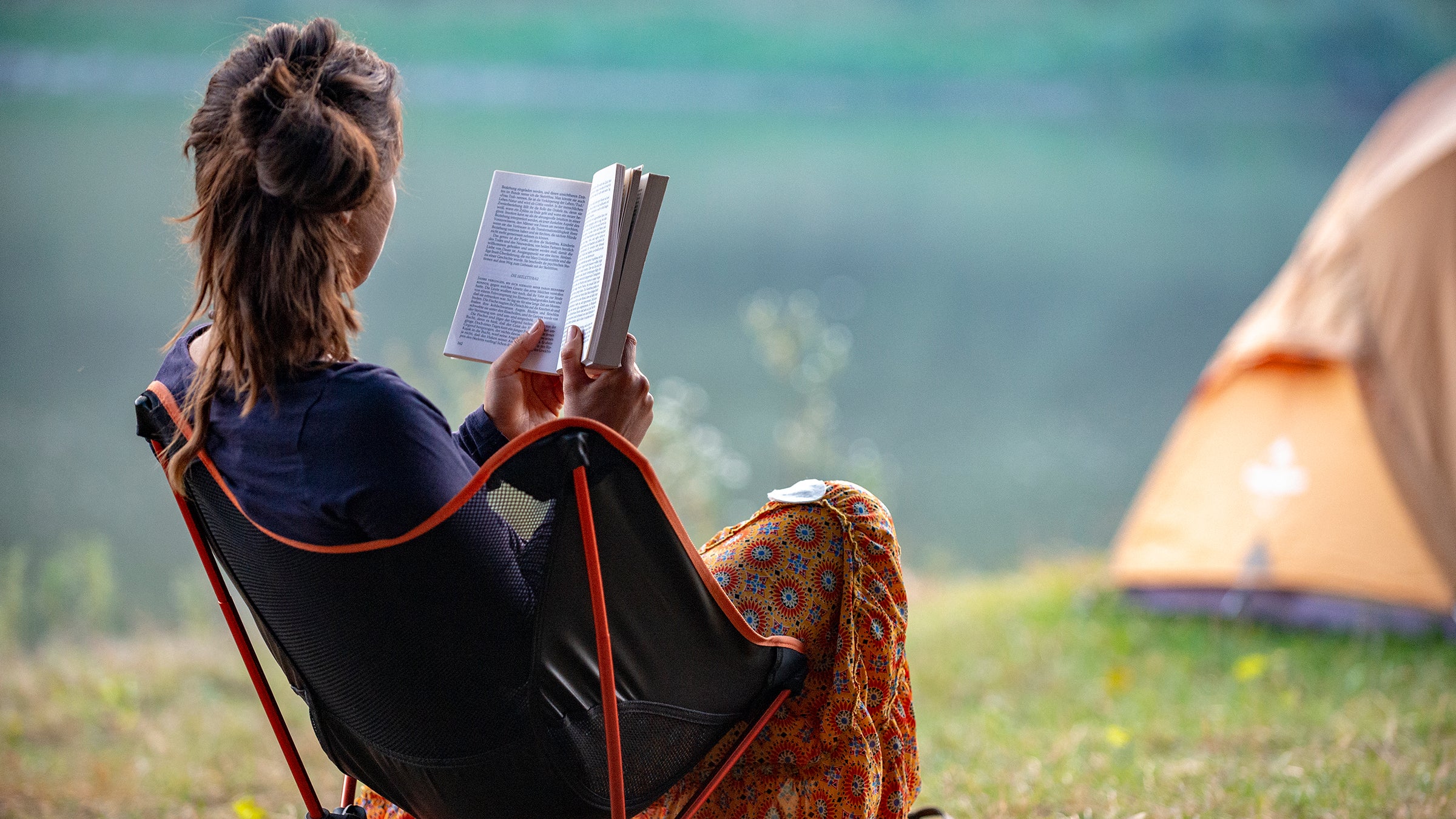 girl reads a book by the river. Ukraine. Chernihiv.