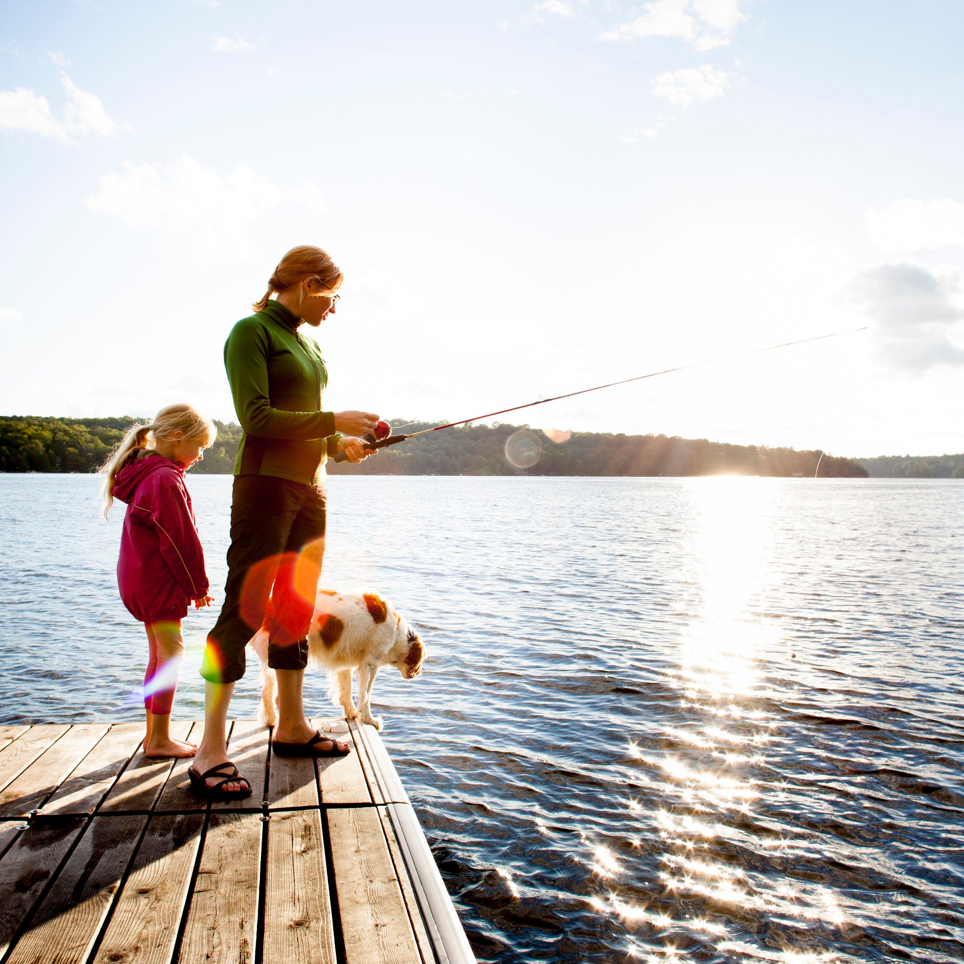 Mother Daughter And Dog Fishing From Dock At Cottage