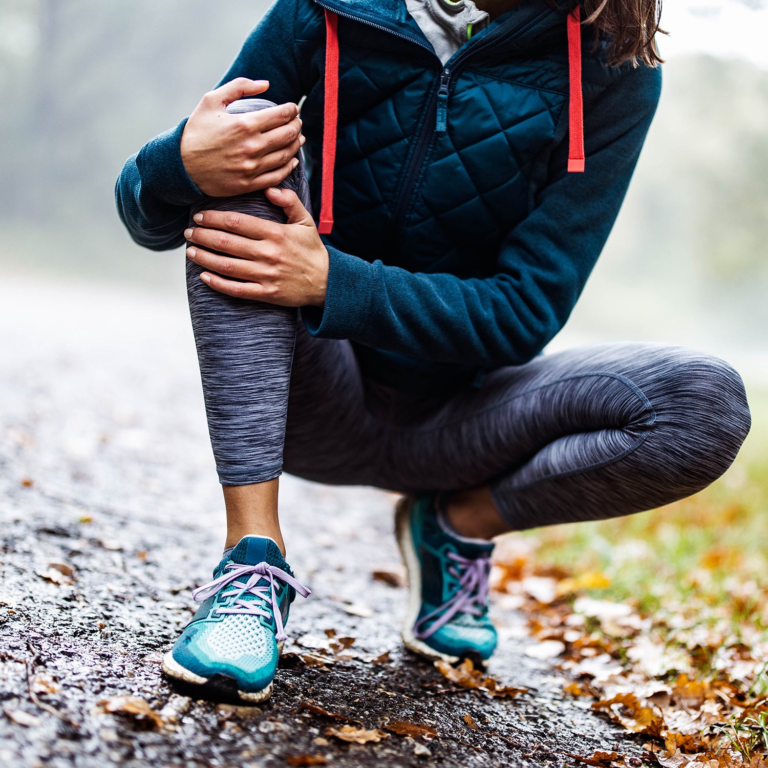 Unrecognizable athlete holding her knee in pain at the park.