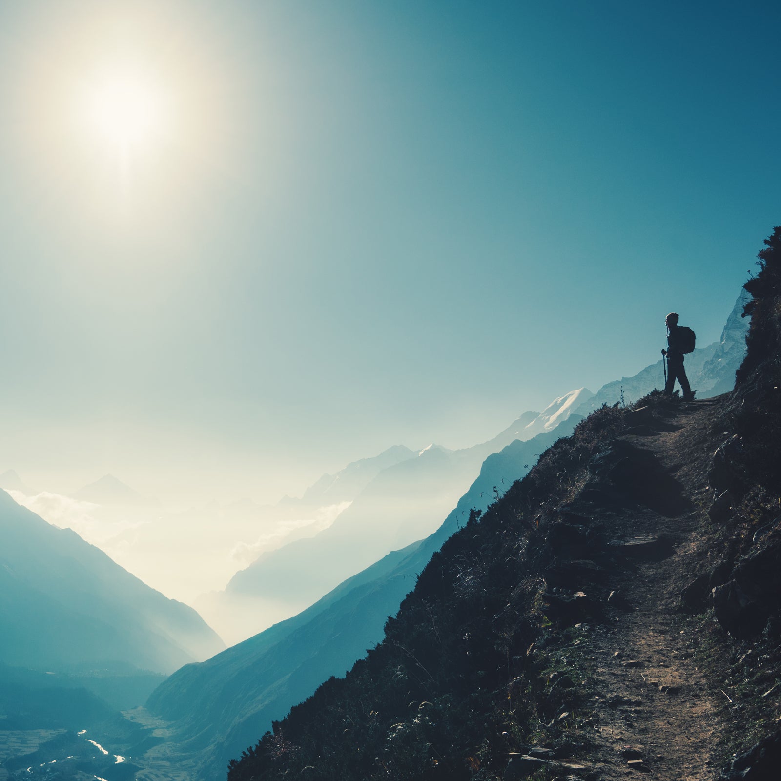 Standing woman on the hill against mountain valley at bright sunny day. Landscape with girl, trail, mountain, blue sky with sun and low clouds at sunset in Nepal. Lifestyle, travel. Trekking
