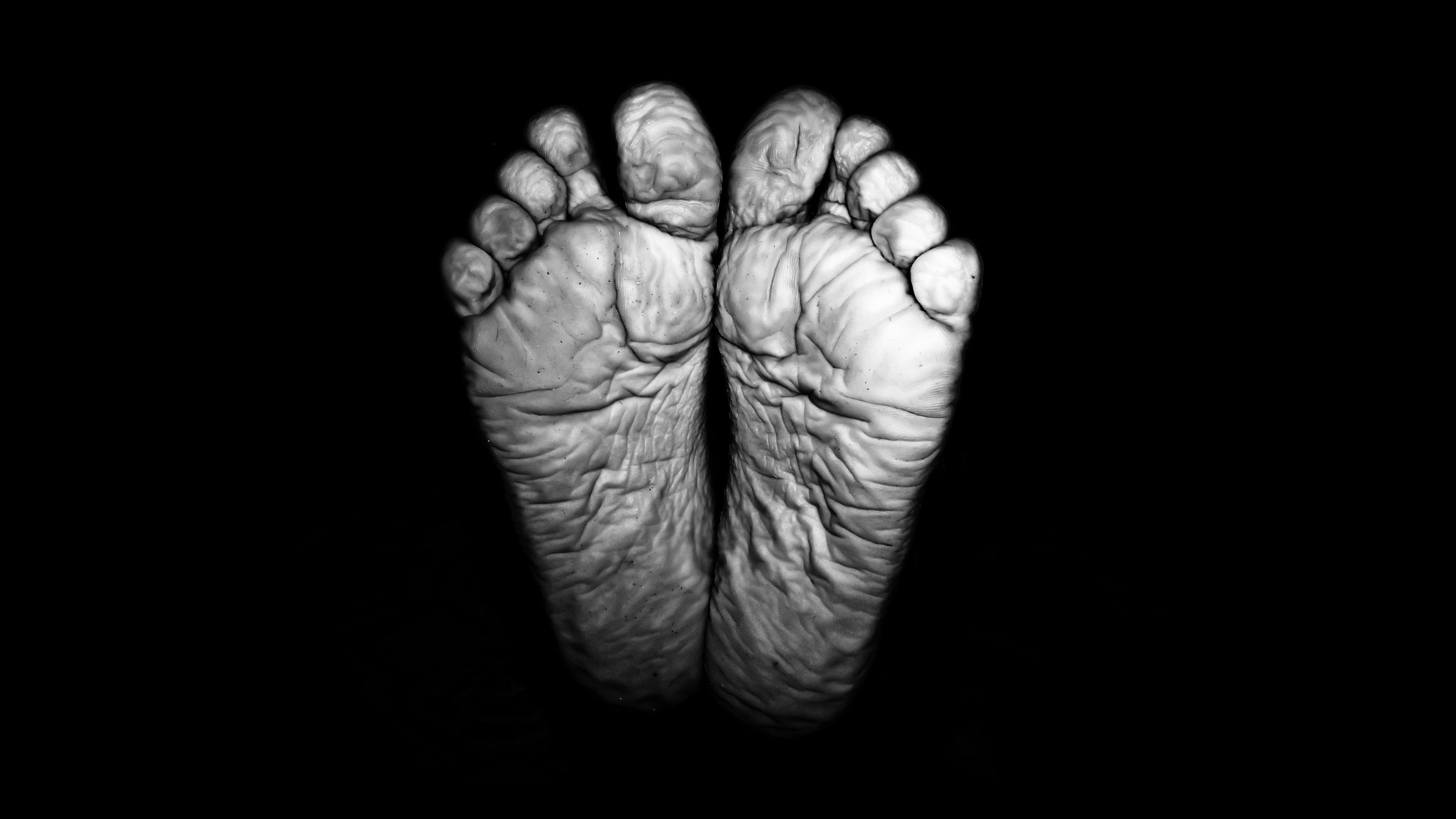 A black and white photo of the bottom of wrinkled feet