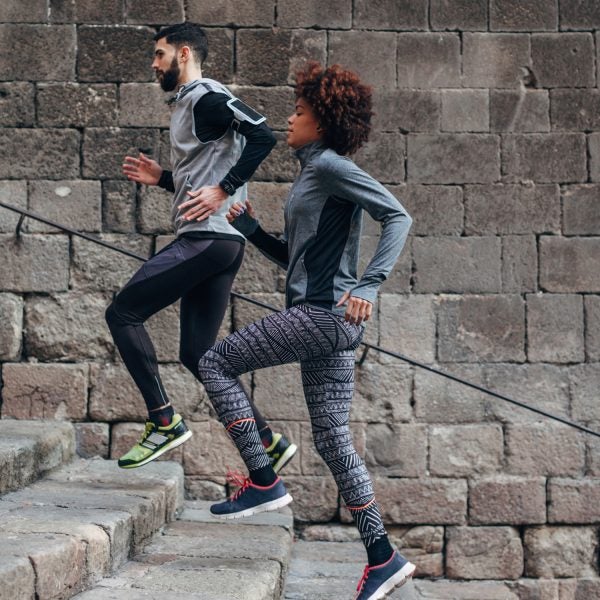 Young Multiethnic Couple Running Of Old Steps Outside.