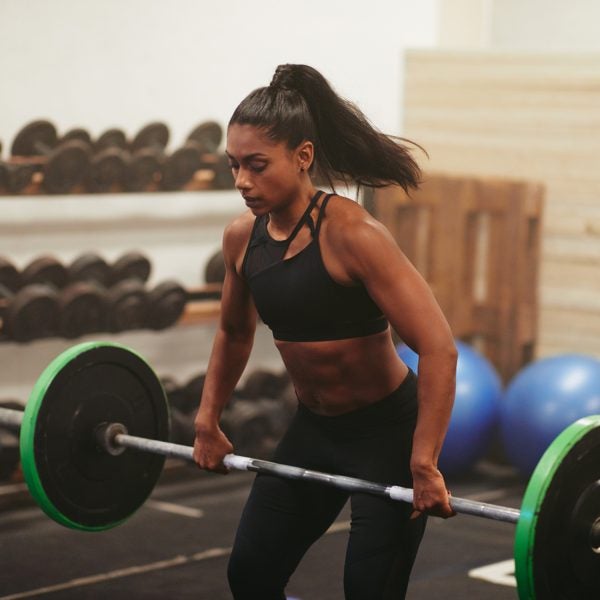 Muscular Young Woman Lifting Weights During A Gym Class