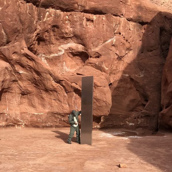A Utah state worker inspecting a metal monolith