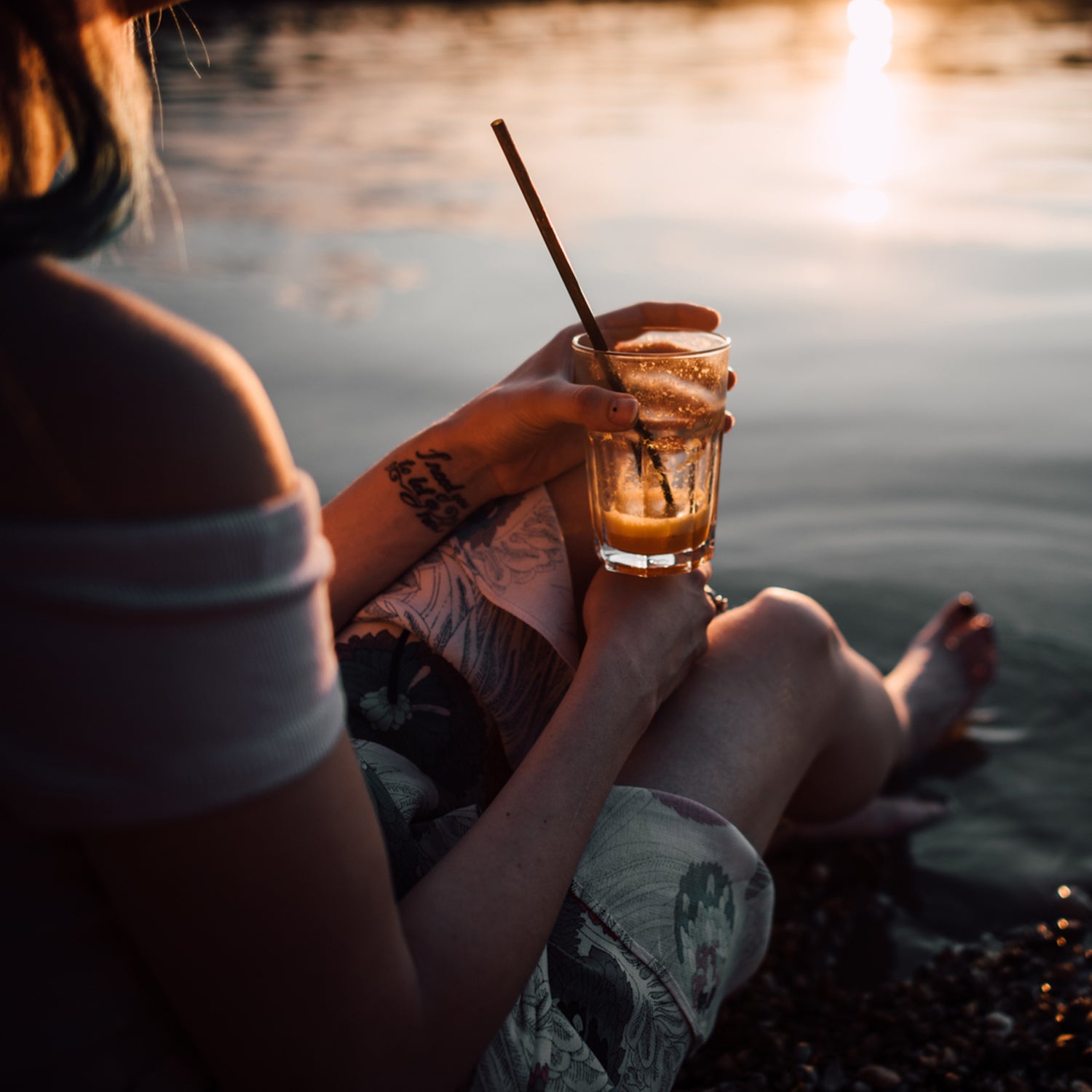 Young Woman Having A Drink And Sitting On The Beach