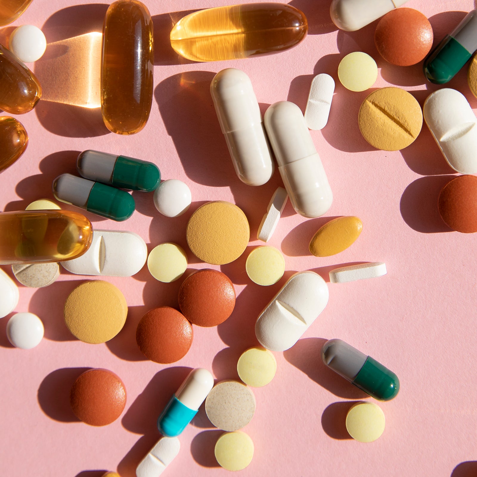 Top view of various pills and tablets on the pink background