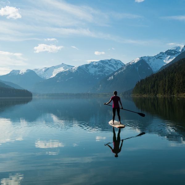 Woman stand up paddle boarding on a pristine mountain lake