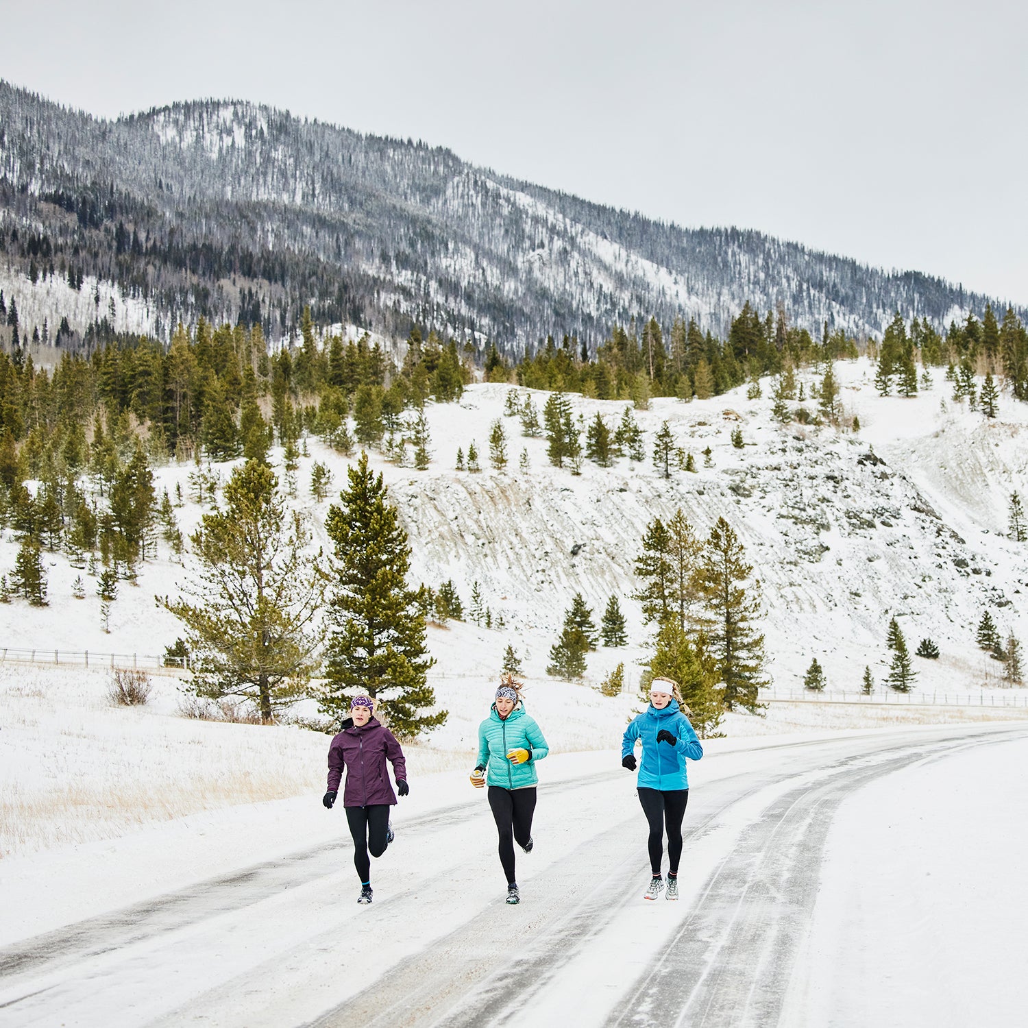 Three female friends on winter run on snowy road