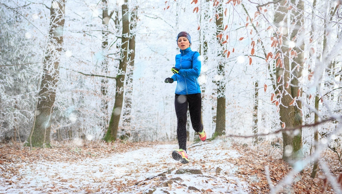 A young woman jogging in the wintry forest.