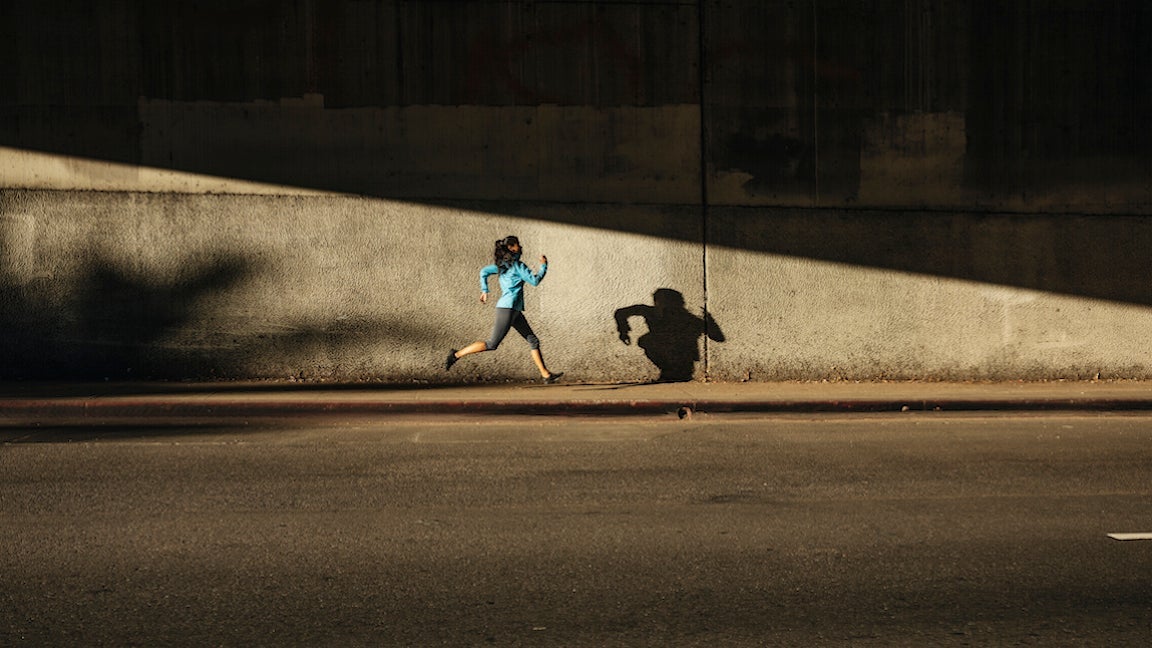 Woman running against wall on city street