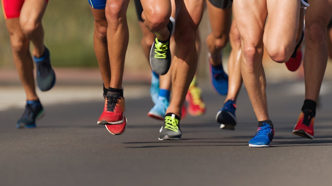 Marathon runners' legs running race on city roads.