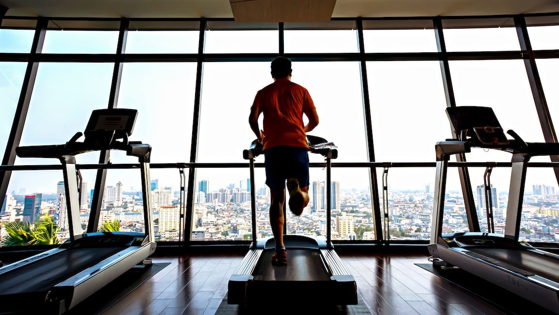 Man running on treadmill overlooking city.