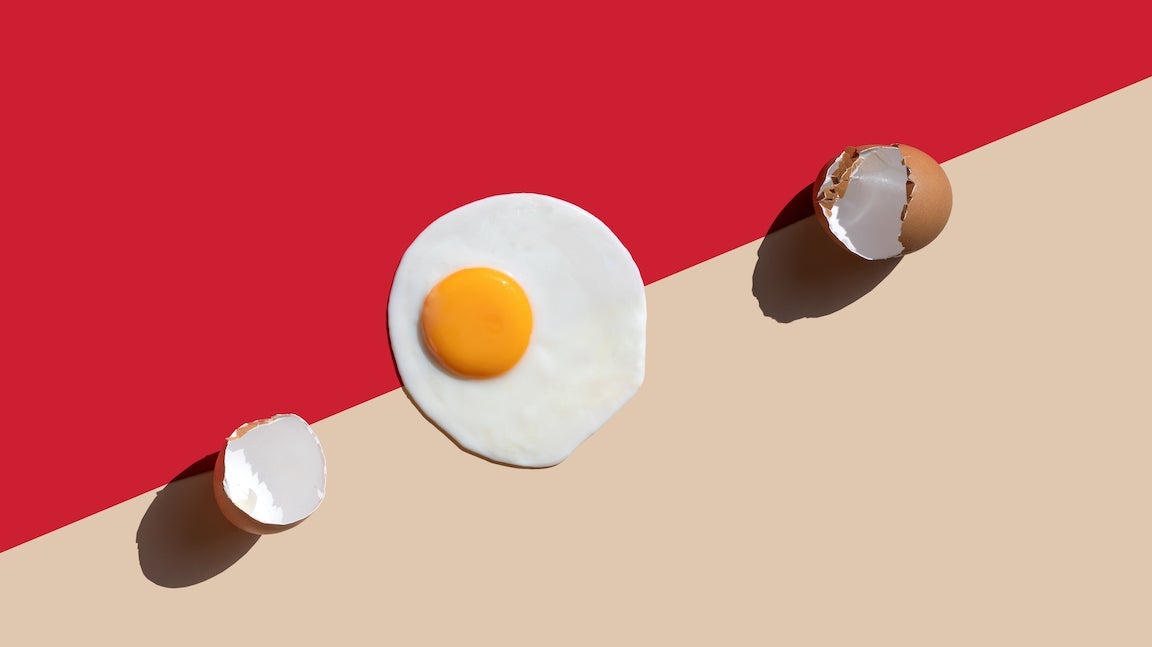 Close-up of the fried egg and egg shell on red-beige background