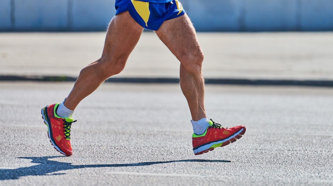 Older man jogging in sportswear on city road, heel striking.
