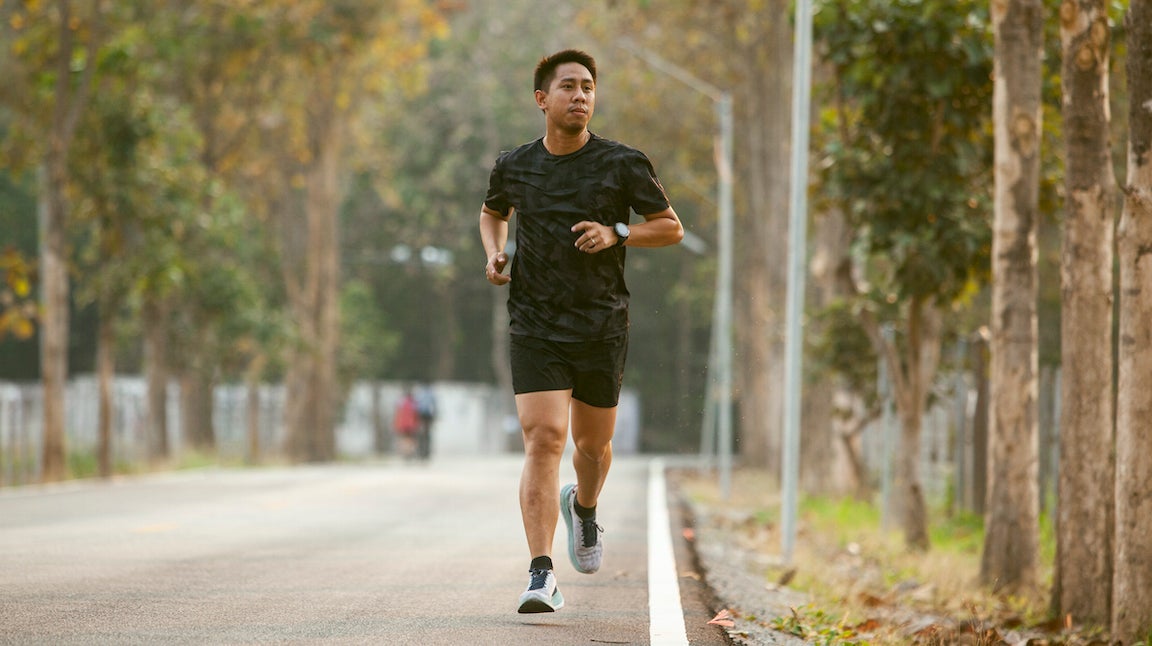 Guy jogging and checking smart watch between workout jogging outdoors.