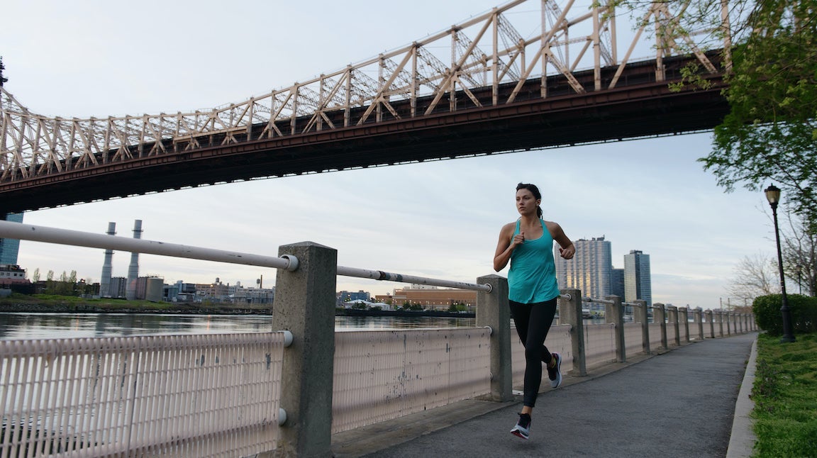 Woman running under NYC bridge.