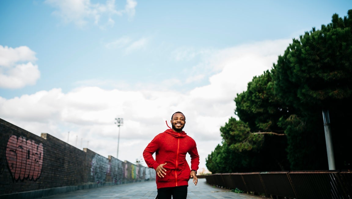Portrait of young black guy in casual clothing, running on the street.