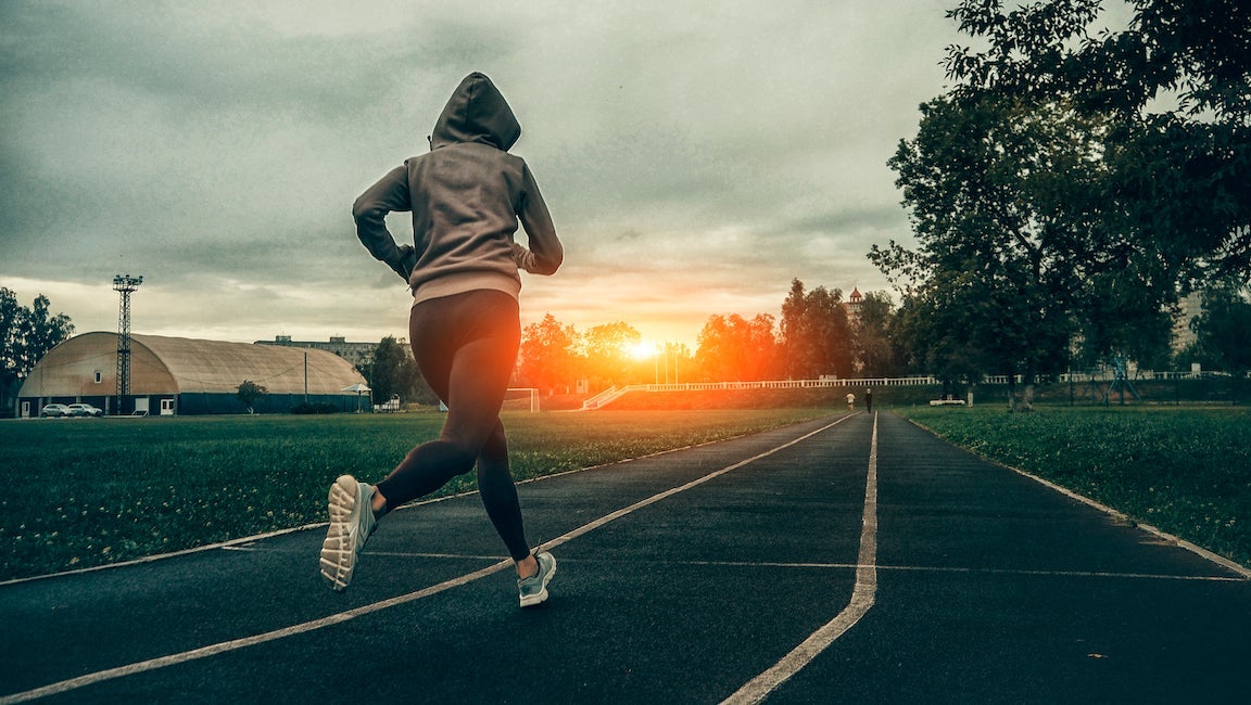 Women running on track as sun is setting.