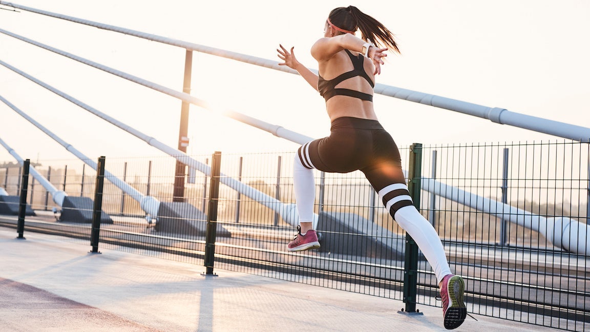 Young woman sprinting in the city over a bridge.