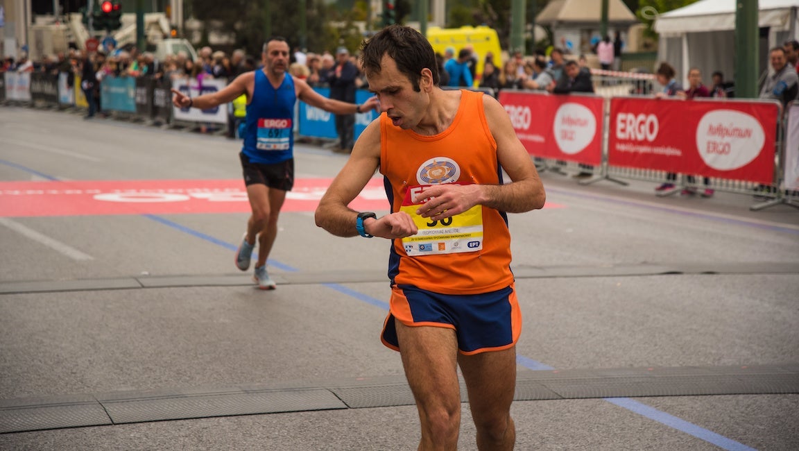 Participant looking at his watch to check the time it took to complete. Steady race pacing is key to marathon progression.