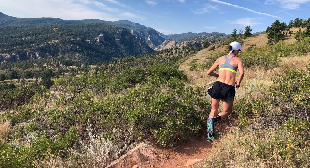 Woman running hills on mountain trail