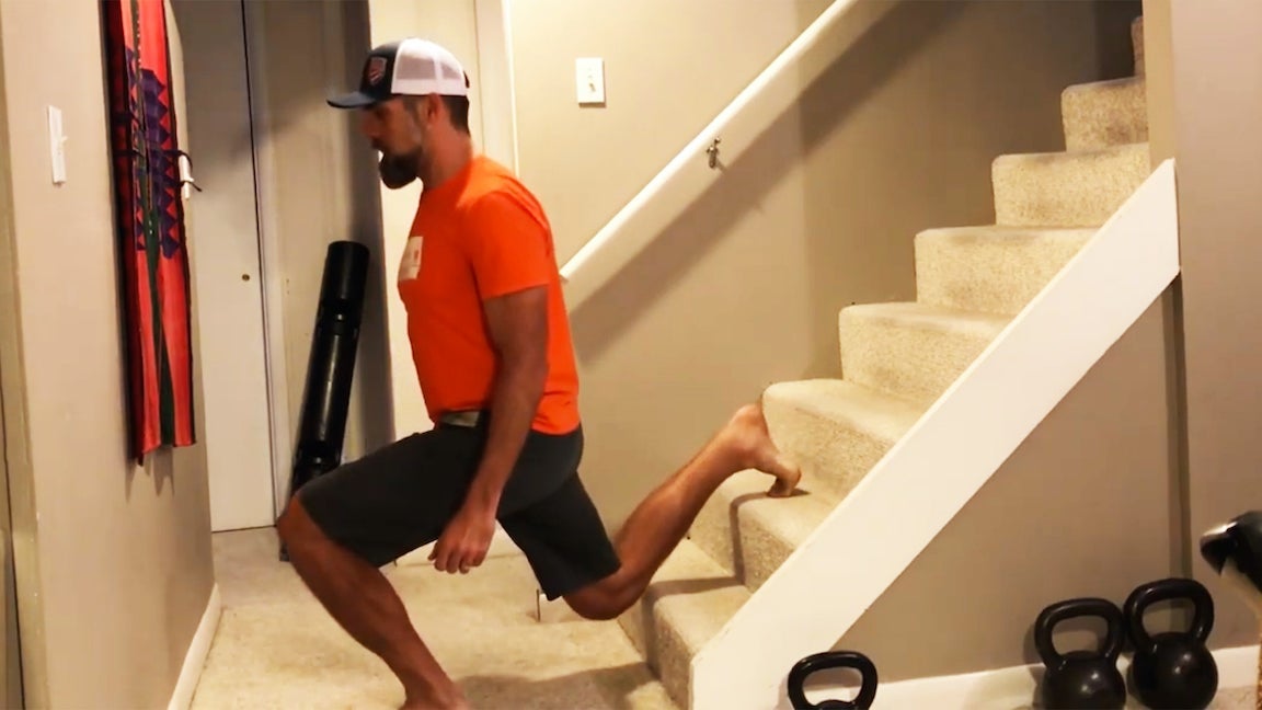 Man in orange shirt doing elevated lunge with back leg on staircase.