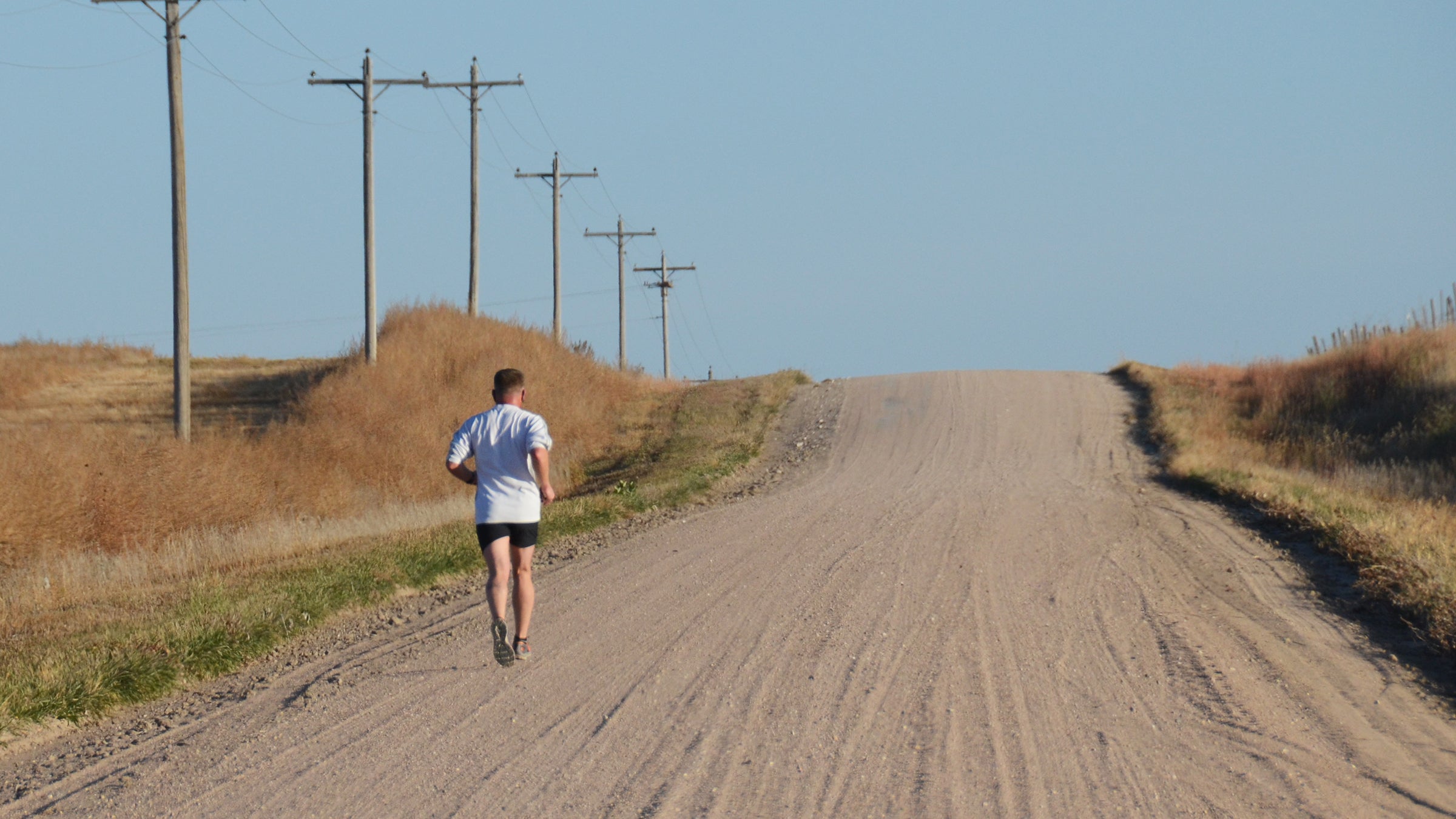 solo runner on dirt road hill