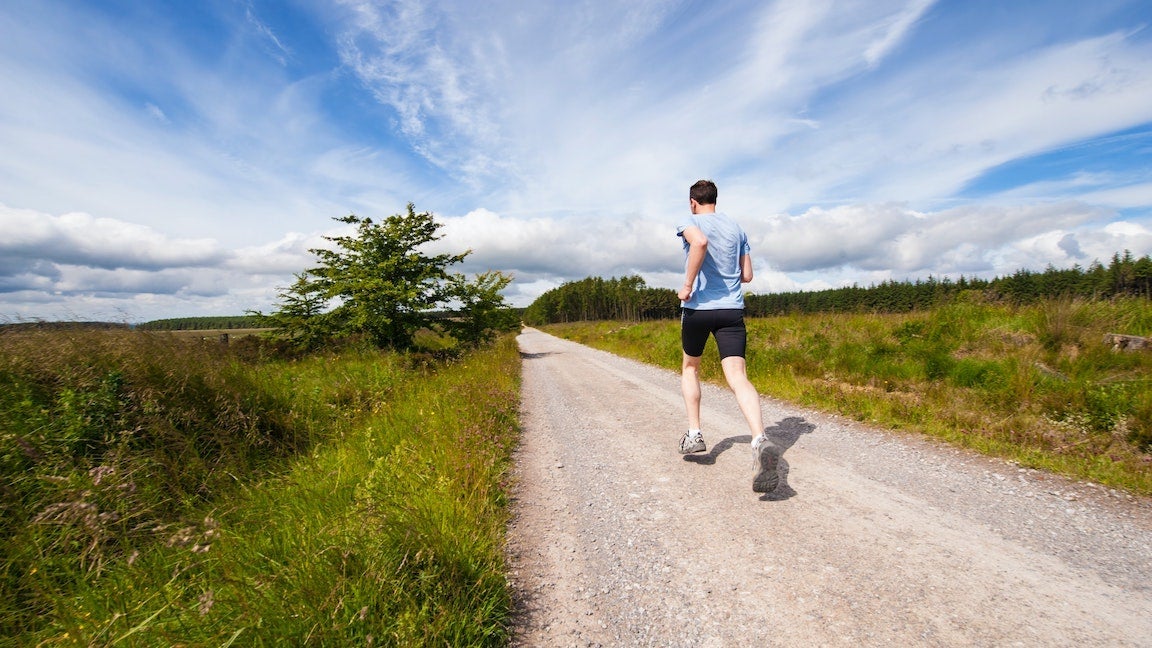 Man running on gravel road.