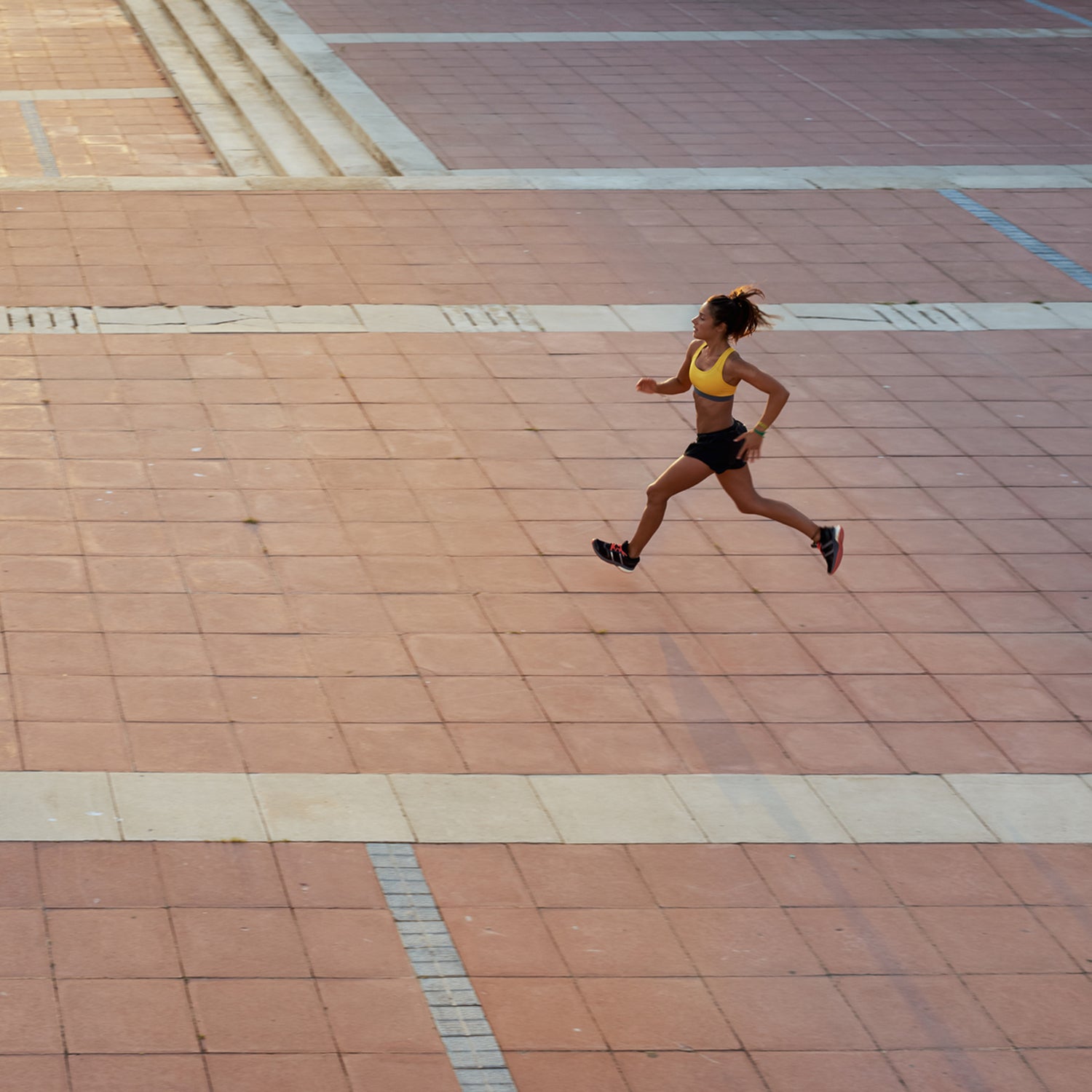 Runner running at high speed on empty paved square