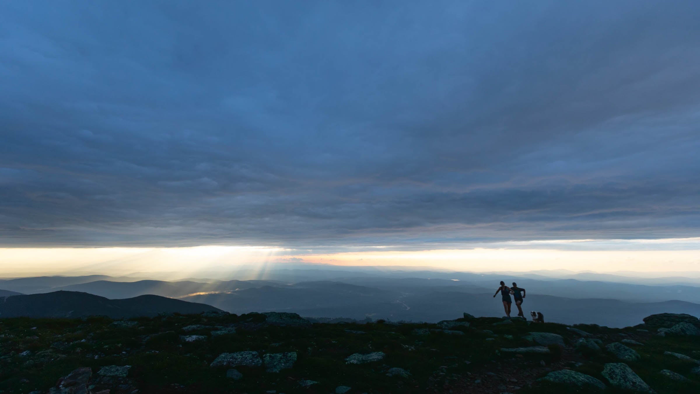 A couple mountain running under an overcast sky