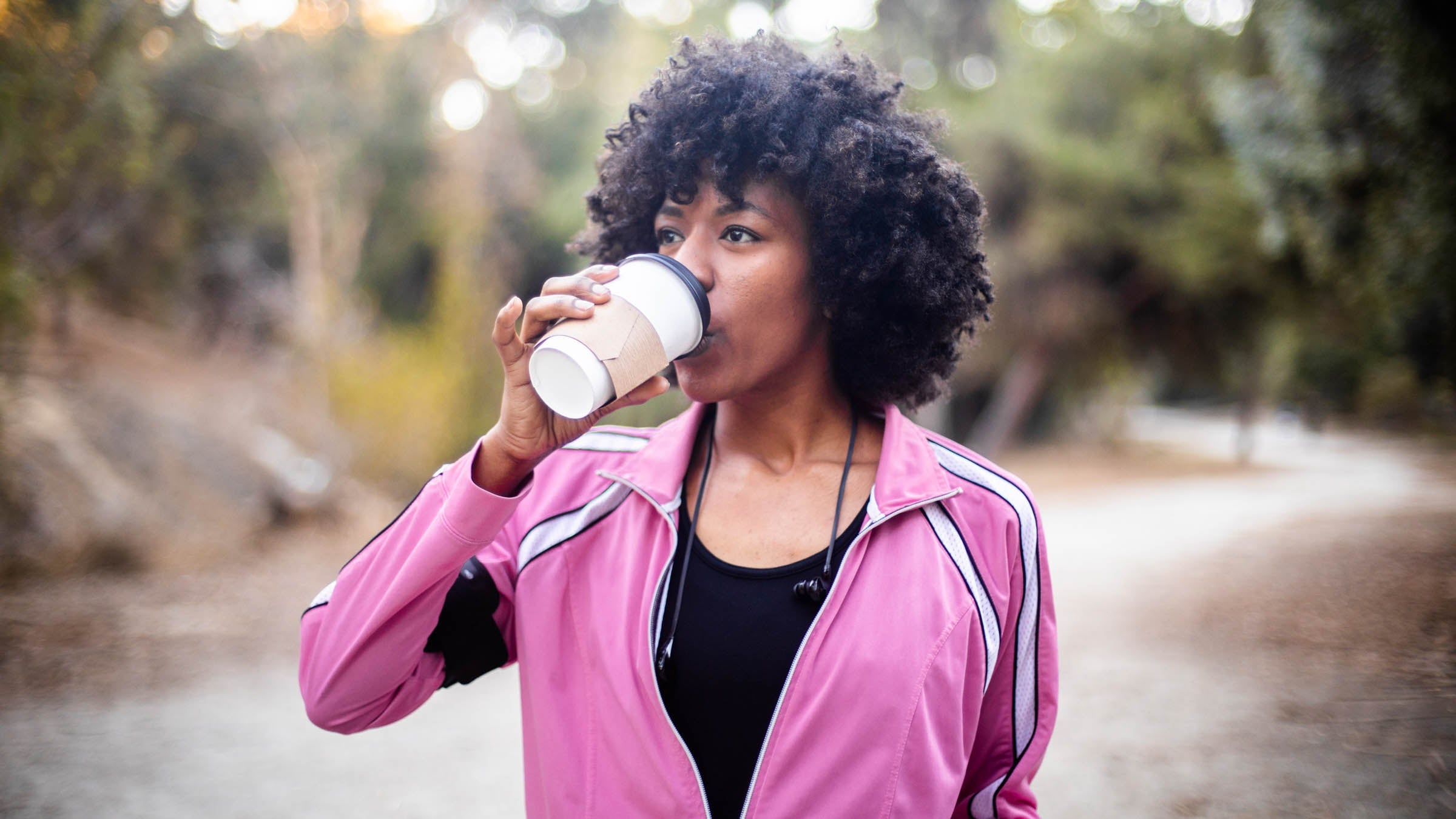 A young black woman walking with a cup of coffee