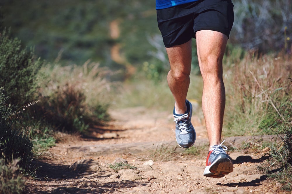 Shot of man's legs while he runs on trail.