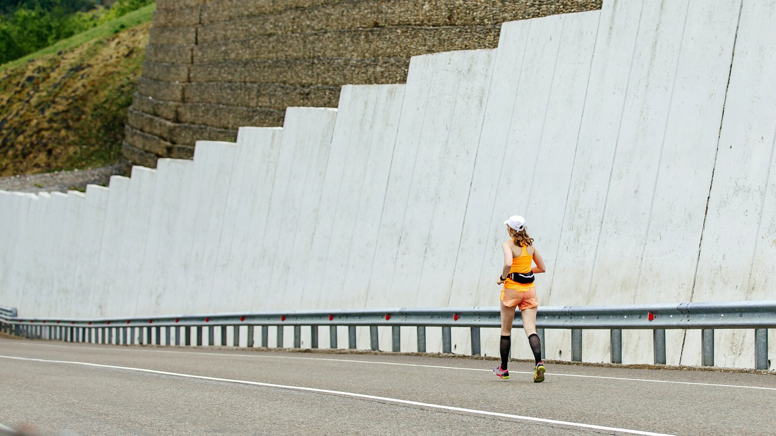 woman running alone on a road, downhill