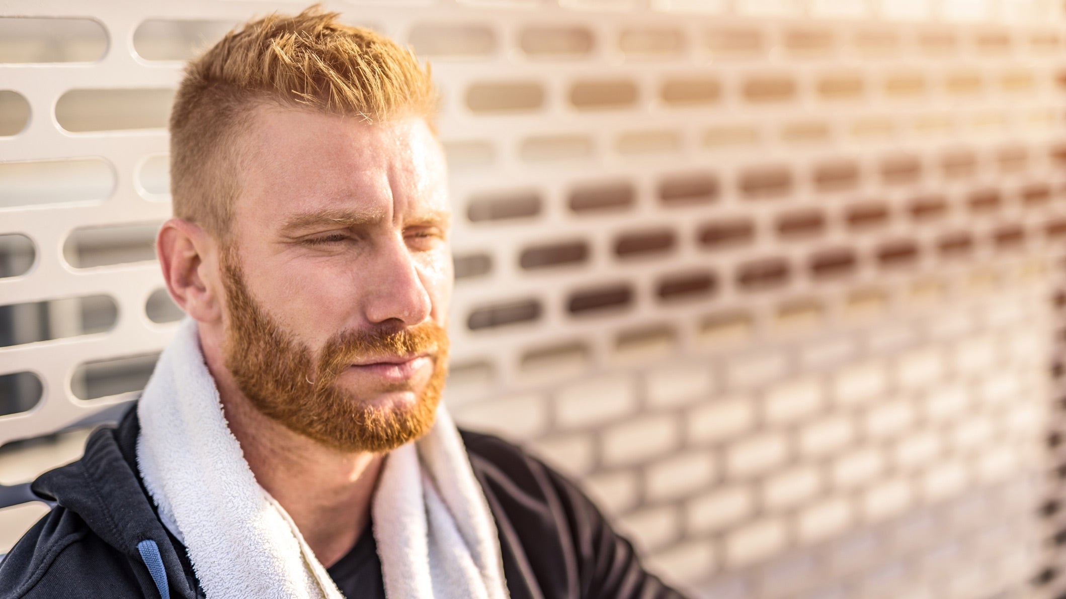 Bearded man sitting against patterned wall