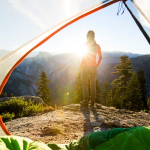 A woman taking in the view of Half Dome at sunrise while camping in the mountains.