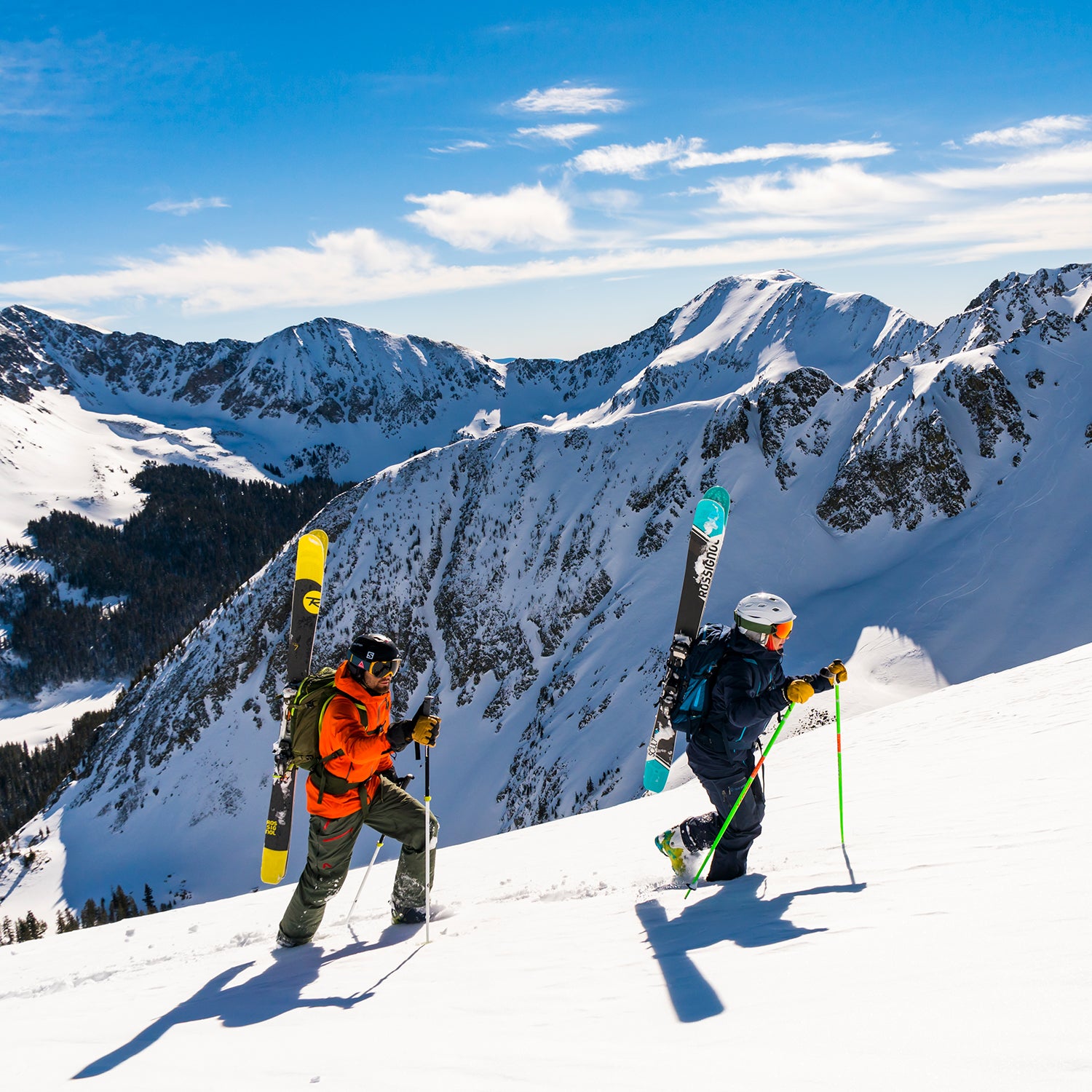 Skiers carrying gear up a mountain