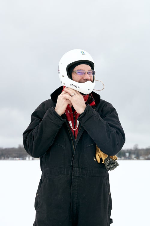 An iceboat racer puts on his helmet between runs.