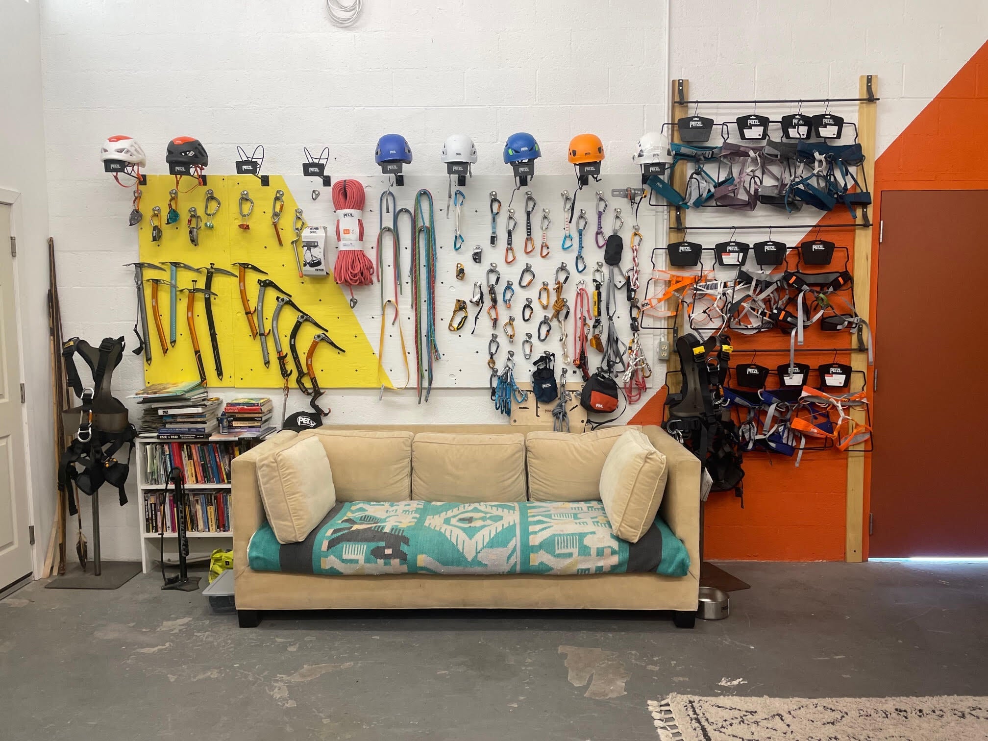 a sales rep showroom with climbing gear hanging on wall an beige couch