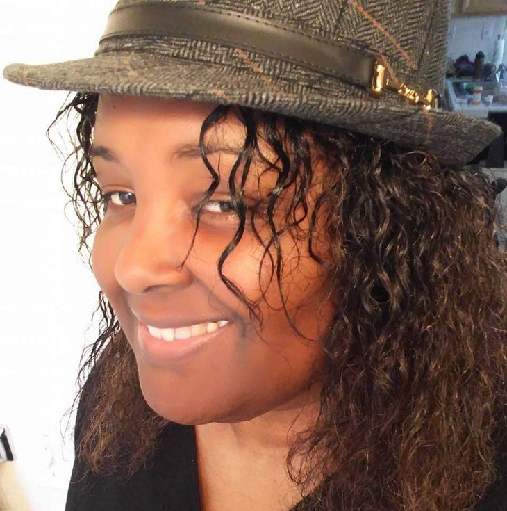 Smiling Balck woman with long hair and wearing a fedora | allyship