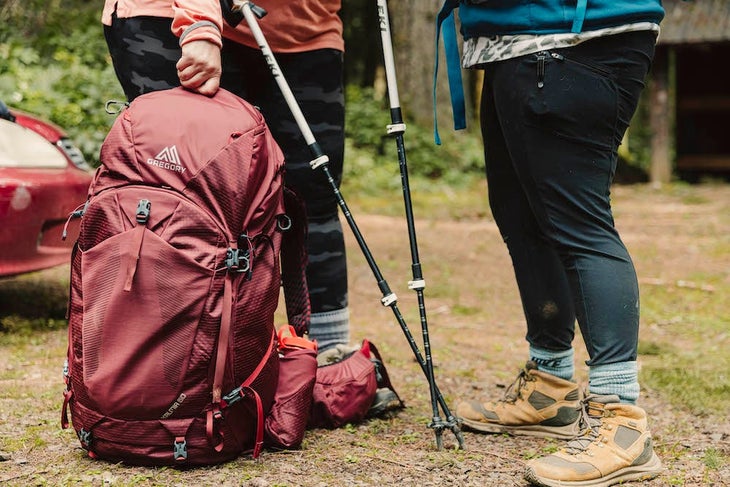 Backpack sitting on the ground by two people's feet