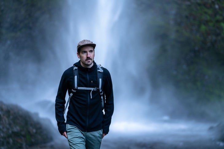 Man in Ibex jacket standing in front of waterfall