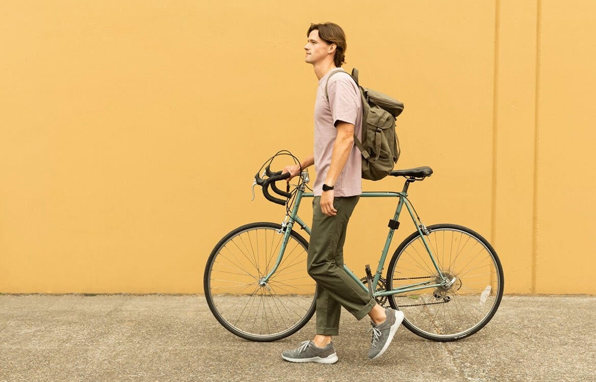 Man walking with bicycle against and orange wall