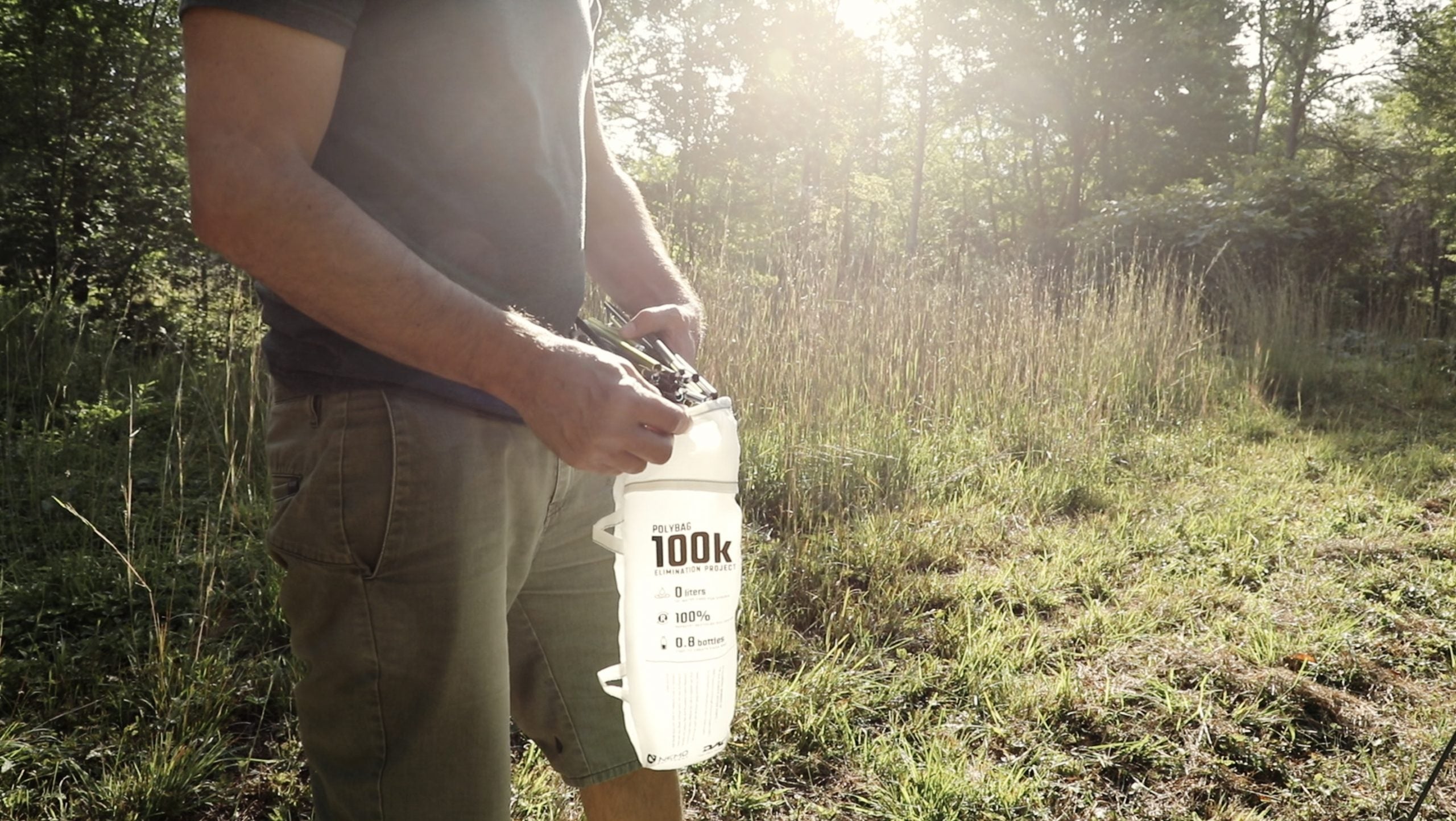 Man standing in a meadow inserting tent poles into a pouch labeled