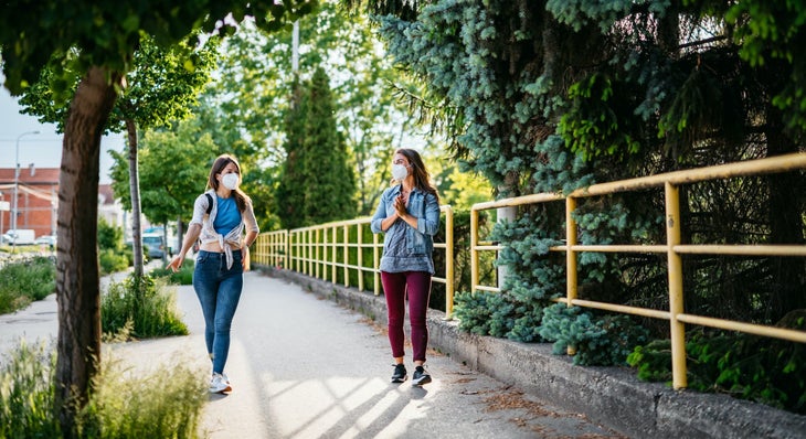 Two women walking along a path with face masks on