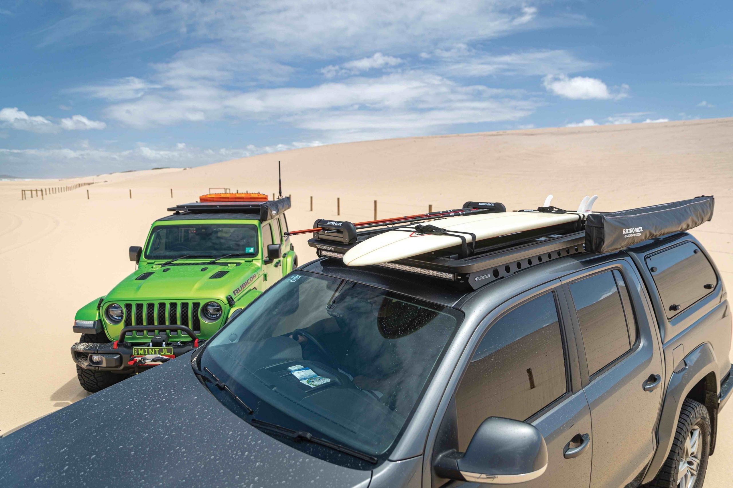 Two jeeps on the beach with roof racks