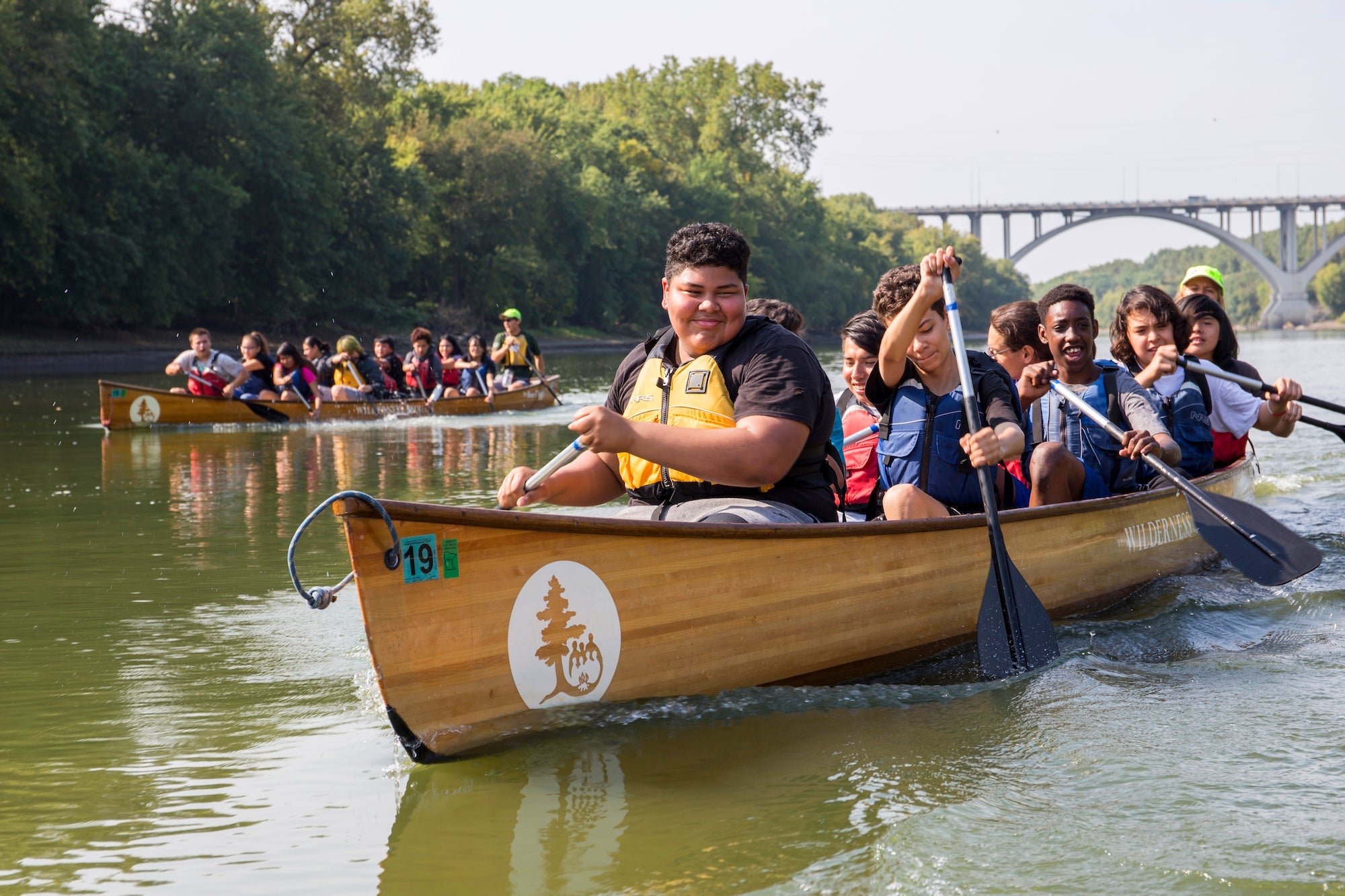 A group of kids paddling a wooden canoe in Thrive Outside program