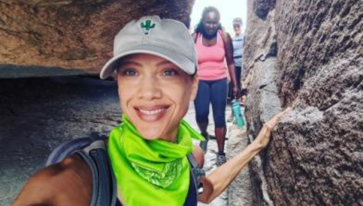 Woman hiking in a slot canyon with tan cap and bright green neck bandana | Marketing