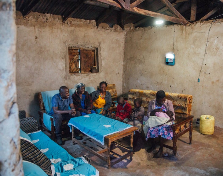 biolite SHS_lifestyle_1 Biolite lighting illuminates a concrete home in Africa, where a family gathers around a table.
