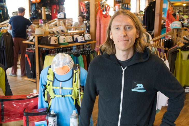 brendan madigan alpenglow Brendan Madigan. Long haired smiling man in black hoodie standing in a retail shop